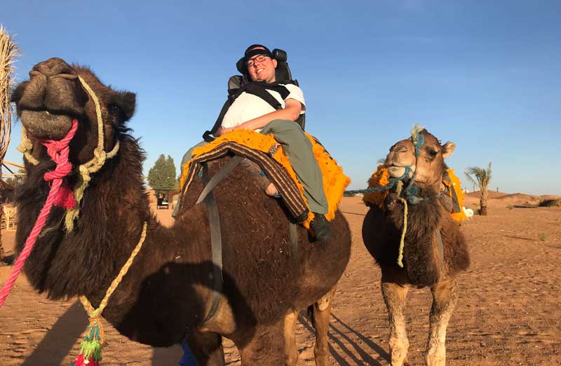 Cory riding a camel on a trip